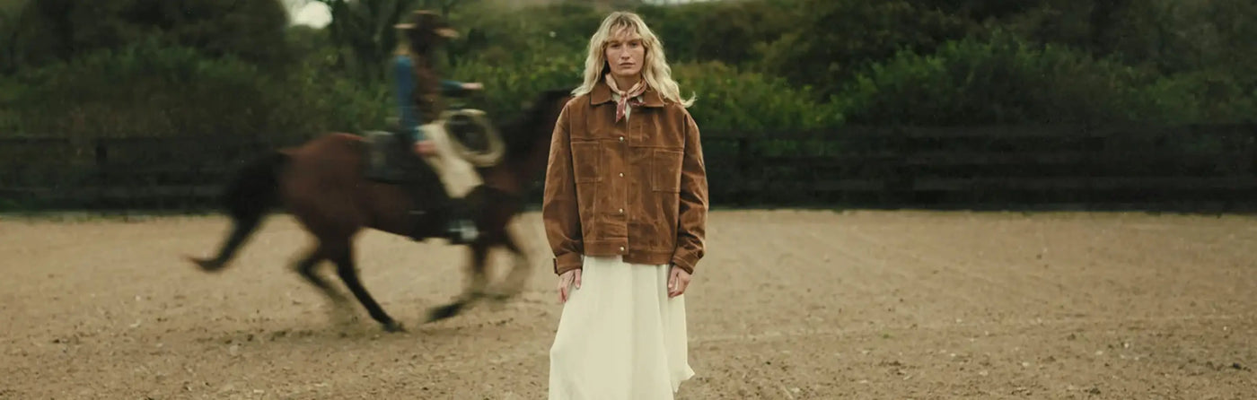 A woman wearing a pair of Durango Western Boots stood in front of a galloping horse