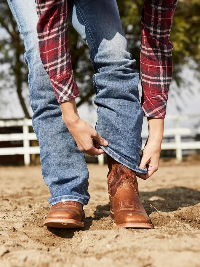 Person putting on a pair of Durango Western Boots on a sunny day.