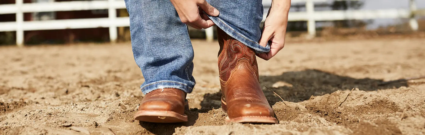 Person putting on a pair of Durango Western Boots on a sunny day.